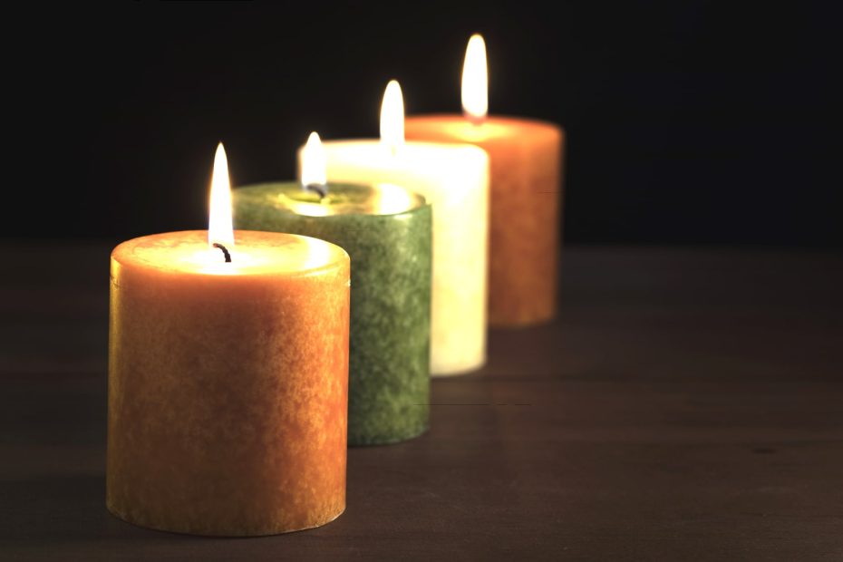 Quatre bougies alignées sur une table en bois.